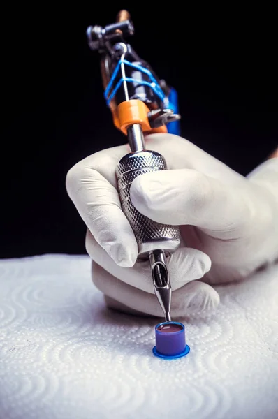 Hand of a tattoo artist with a tattoo gun. — Stock Photo, Image