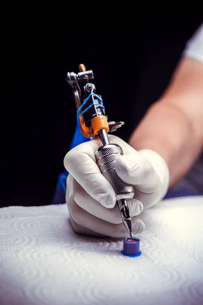 Tattooers hand and a tattoo machine. — Stock Photo, Image
