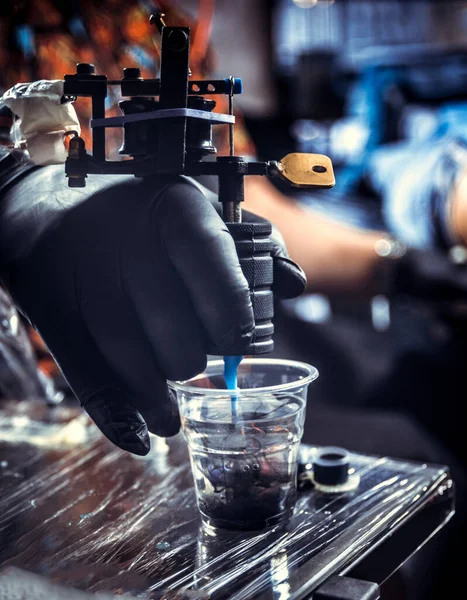 Hand of tattoo specialist with a tattoo gun. — Stock Photo, Image