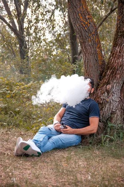 Sigara tiryakisi duman tüttürür ve duman çıkarır. Yeni teknoloji sigarası.. — Stok fotoğraf