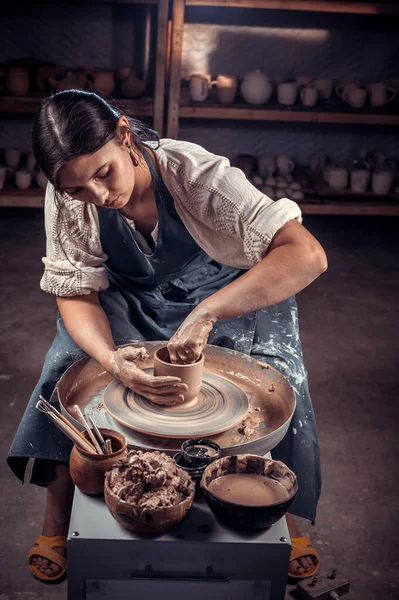 Cerâmica encantadora trabalhando na roda oleiros com argila crua com as mãos. Produção artesanal. — Fotografia de Stock