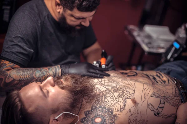 Мастер-татуировщик во время сеанса татуировки — стоковое фото