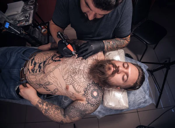 Mestre mostrando processo de fazer uma tatuagem no salão de tatuagem — Fotografia de Stock