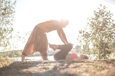Proffesional masöz güneş ışığında canlandırıcı masaj yöntemleri gösterir..
