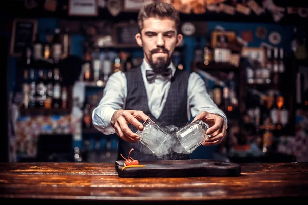 Barman z brodą wlewający świeży napój alkoholowy do szklanek w barze — Zdjęcie stockowe