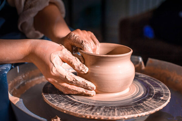 production process of pottery. Forming a clay teapot on a potters wheel.