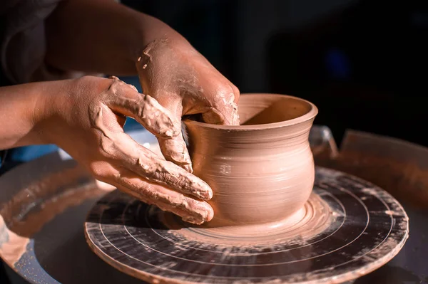 Pottenbakker meesterbeeldhouwer werkt met klei op een pottenbakkerswiel en aan tafel met het gereedschap. Close-up. — Stockfoto