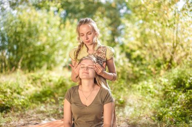 Masaj eğitmeni müşterisine gün ışığında ferahlatıcı bir masaj yapıyor..