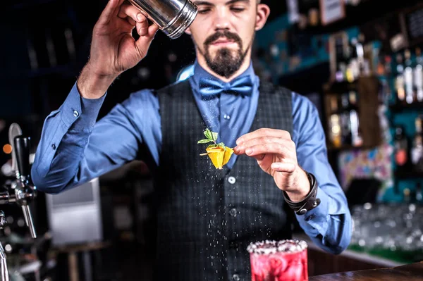 Expert barman umístí dokončovací doteky na nápoj, zatímco stojí poblíž baru pultu v baru — Stock fotografie
