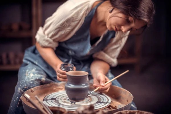 Bella studentessa vasaio crea una nuova ceramica da argilla su una ruota vasai. Artigianato. — Foto Stock