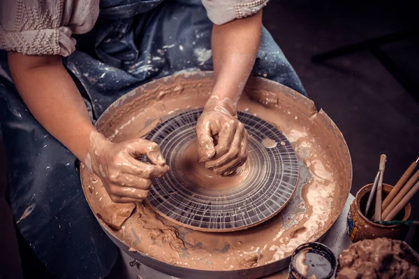 Young and cheerful woman shows how to work with clay and pottery wheel. Close-up. — Stock Photo, Image