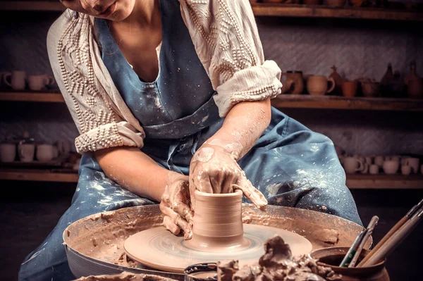 Rzemieślnik siedzi na ławce z ceramicznym kołem i robi gliniany garnek. Produkcja rękodzieła. Zbliżenie. — Zdjęcie stockowe