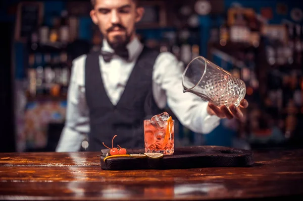 Focado bartender termina intensamente sua criação, enquanto está perto do balcão de bar no pub — Fotografia de Stock