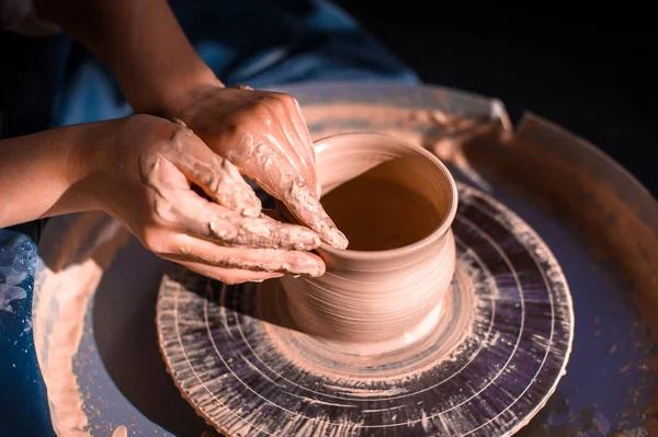 Le mani delle donne. Un vasaio al lavoro. Creare piatti. La ruota dei vasai. Mani sporche nell'argilla e la ruota vasai con il prodotto. Creazione. Ceramista di lavoro. — Foto Stock