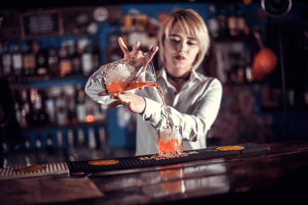 Mladá žena mixolog demonstruje své dovednosti přes pult v nočním klubu — Stock fotografie