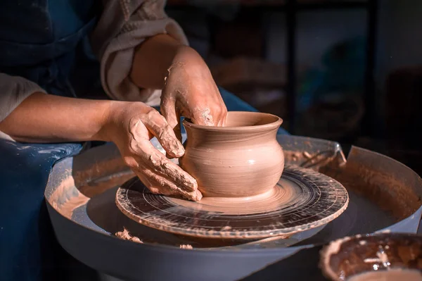 クローズアップ茶色い土の深い器を美しく彫刻し、美しい工房でろくろで余分な粘土を切り落とす女性陶芸家。 — ストック写真