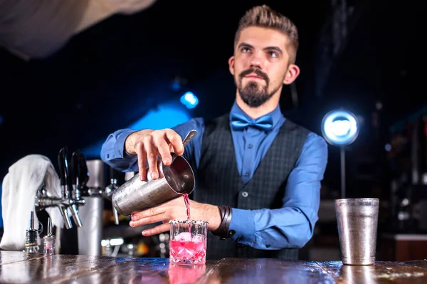 Charismatische vrouwelijke barman siert kleurrijke brouwsel in de nachtclub — Stockfoto