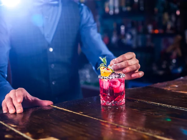 Experienced barkeeper formulates a cocktail while standing near the bar counter in nightclub — Stock Photo, Image