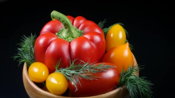 Un gran pimiento rojo, cuatro tomates amarillos, un tomate rojo y ramitas de eneldo están en un tazón de madera marrón redondo — Vídeo de stock
