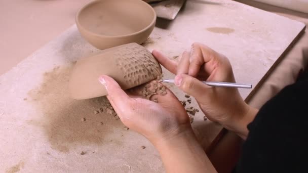 Een pottenbakker versiert een kleikom — Stockvideo