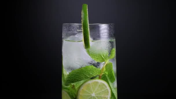 Närbild av ett roterande mistat glas mojito med limeskivor, myntablad och isbitar — Stockvideo