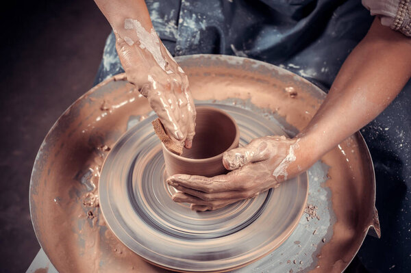 hands of potter do a clay pot
