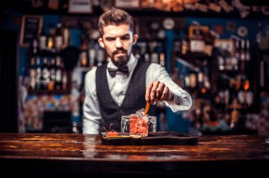 Young bartending mixes a cocktail while standing near the bar counter in bar clipart