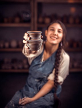 Esnaf atölyede bitmiş kil ürünü gösteriyor. El işi..