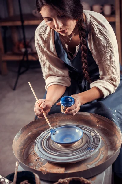 Le mani delle donne. Un vasaio al lavoro. Creare piatti. La ruota dei vasai. Mani sporche nell'argilla e la ruota vasai con il prodotto. Creazione. Ceramista di lavoro. — Foto Stock