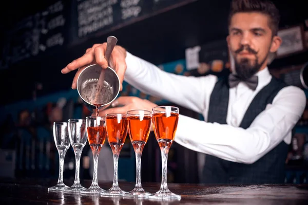 Okouzlující barman nalévá pití, zatímco stojí u baru v baru. — Stock fotografie