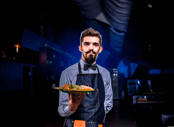 Επαγγελματίας σερβιτόρος σερβίρει σαλάτα σε μαύρο φόντο. — Φωτογραφία Αρχείου