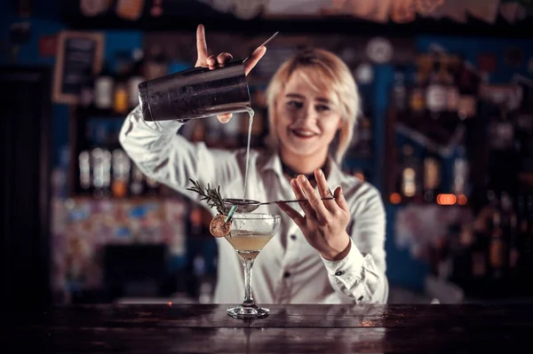 Mulher confiante tapster faz um show criando um coquetel enquanto está perto do balcão de bar no bar — Fotografia de Stock