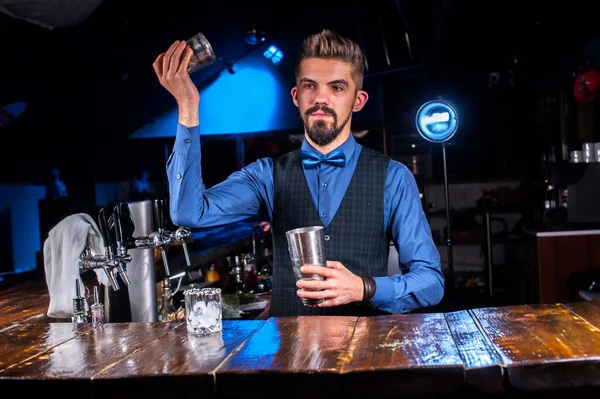 Gericht barkeepen versiert kleurrijke brouwsel tijdens het staan in de buurt van de bar teller in bar — Stockfoto