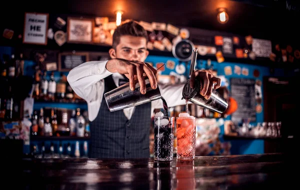 Barman expérimenté mélange un cocktail tout en se tenant près du comptoir du bar dans le bar — Photo