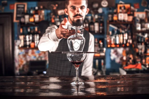 Barman confiante demonstra o processo de fazer um coquetel enquanto está perto do balcão do bar no bar — Fotografia de Stock