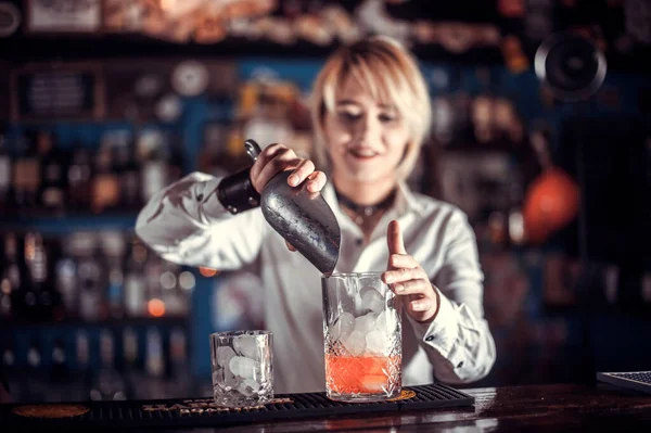 Portrét dívky barman umístí dokončovací doteky na nápoj v baru — Stock fotografie