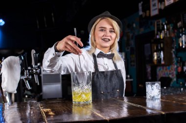 Kız barmen salonda kokteyl hazırlıyor.