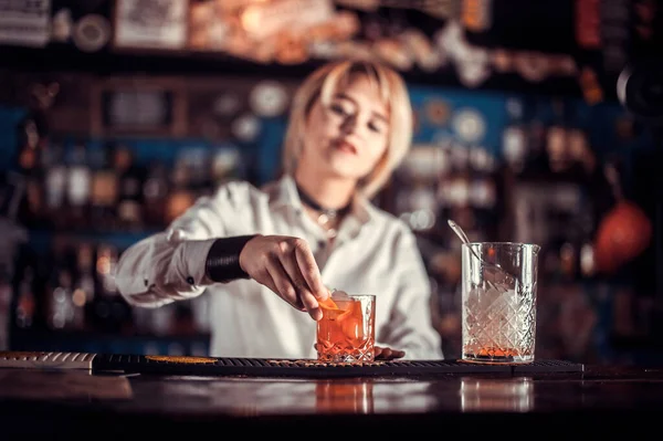 Sweet barmaid formulates a cocktail while standing near the bar counter in pub — Stock Photo, Image