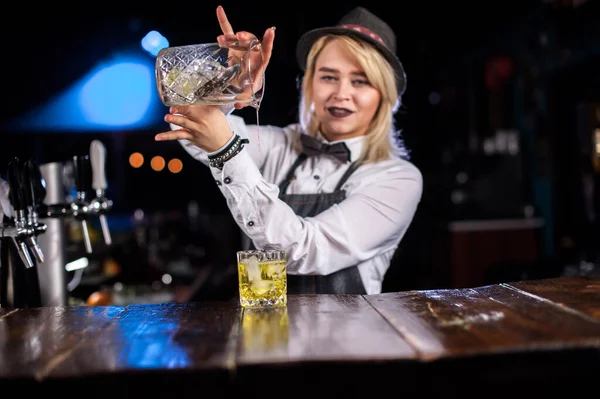 Бармен-девушка готовит коктейль за барной стойкой — стоковое фото