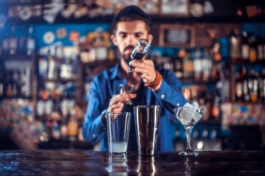 Çekici barmen barda kokteyl yaratarak şov yapıyor.