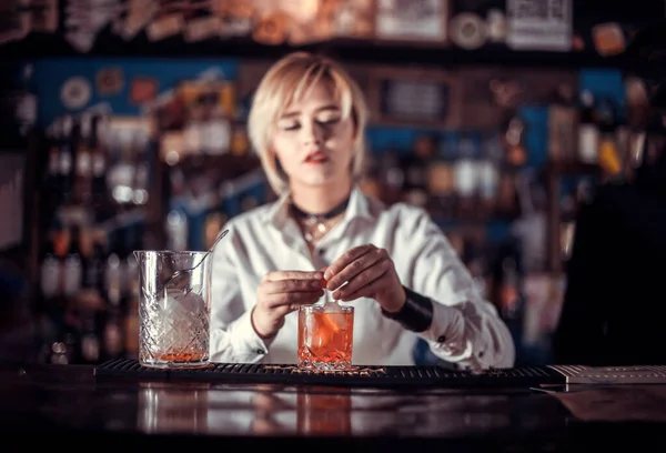 Retrato de mujer camarera sorprende con sus visitantes barra de habilidades mientras está de pie cerca del mostrador de bar en la discoteca — Foto de Stock