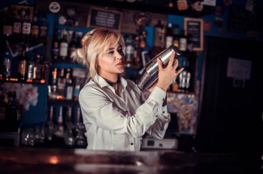 Kız barmen salonda kokteyl hazırlıyor.