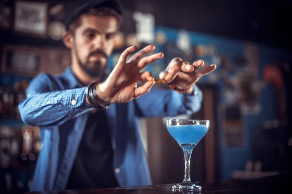 Barman z brodą umieszcza wykończenie na drinku stojąc przy barze w klubie nocnym — Zdjęcie stockowe