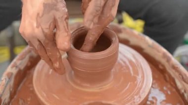 Bir çömlekçi kendi elleriyle çömlek çarkında dönen bir çömlekçiye şekil veriyor.