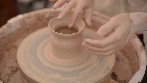 Гончар використовує палець, щоб сформувати глиняний горщик, який обертається на гончарному колесі — стокове відео