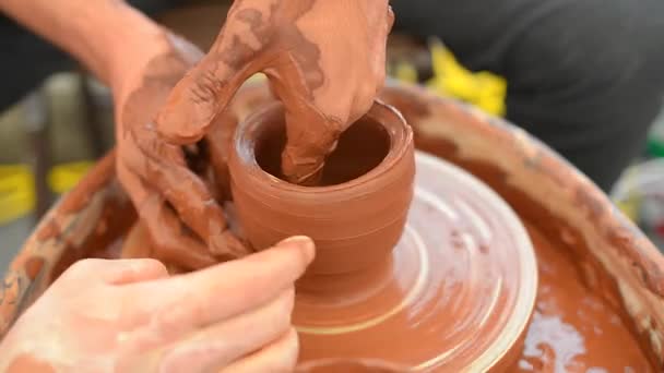 Two potters with his hands are shaping a clay pot rotating on a potters wheel — Stock Video