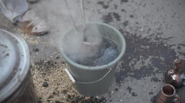 Bir çömlekçi bitmiş kil testisini bir kova suyun içinde soğutuyor.
