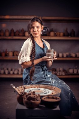 Sanatçılar, çömlekçilik atölyesinde bitmiş kil ürünü gösteriyor. Halk el işi..