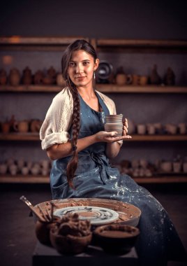 Çömlek yapan genç ve güzel bir bayan. Tekerlekli sandalyedeki ıslak çamurdan heykeltıraş. Halk sanatı.