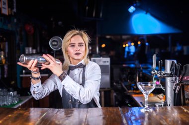 Odaklanmış barmen, barda tezgahın yanında dururken kokteyl yapma sürecini gösteriyor.